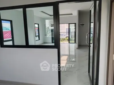 Modern interior with glass partitions and marble flooring, abundant natural light.