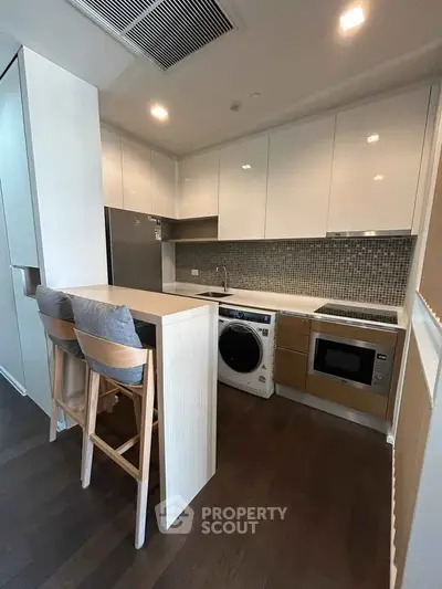 Modern kitchen with sleek cabinetry, integrated appliances, and cozy breakfast bar seating.