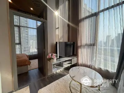 Sunlit modern living room with floor-to-ceiling windows offering a panoramic city view, complemented by sheer curtains and stylish furnishings.