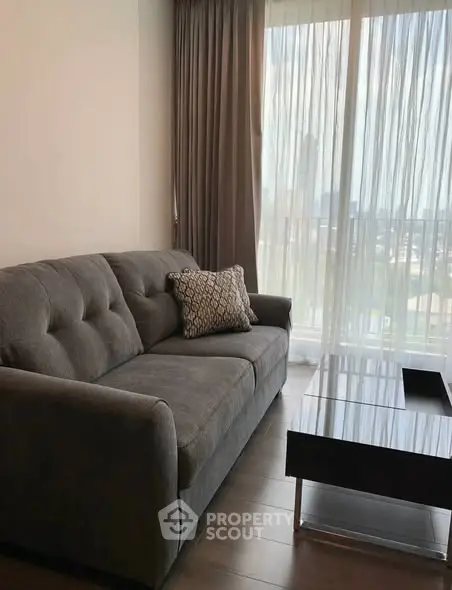 Modern living room with stylish gray sofa and large window offering natural light.