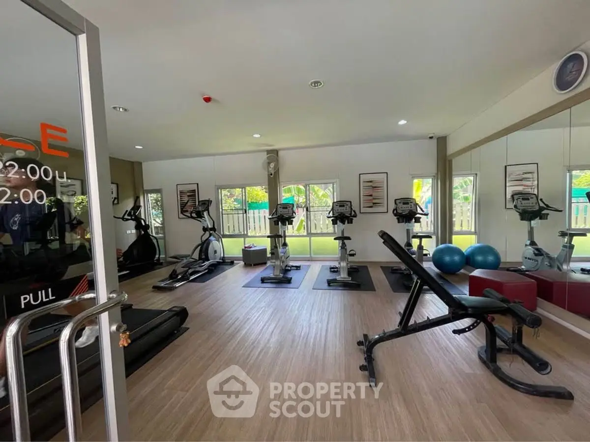 Modern gym with state-of-the-art equipment and large windows in a residential building.