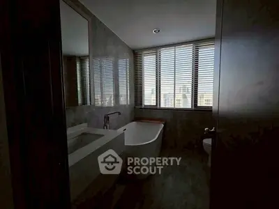 Luxurious bathroom with modern bathtub and city view through large windows.