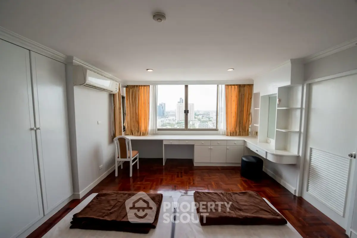Spacious bedroom with city view, featuring built-in storage and elegant wooden flooring.