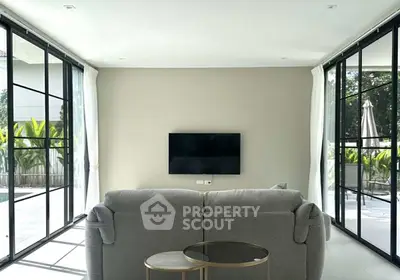 Modern living room with large windows and poolside view, featuring sleek furniture and minimalist design.