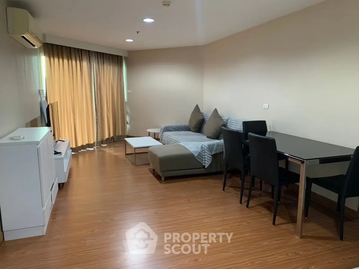 Spacious living room with modern furniture and wooden flooring in a cozy apartment.