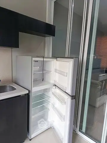 Modern kitchen with open fridge and sleek cabinetry in a contemporary apartment.