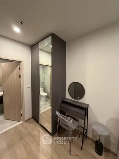 Modern bedroom with sleek wardrobe and vanity set, adjacent to a stylish bathroom.