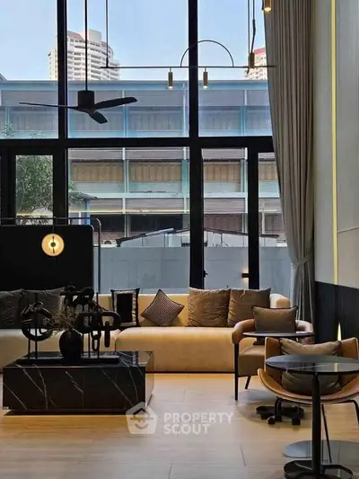 Modern living room with floor-to-ceiling windows and stylish furniture in urban setting.
