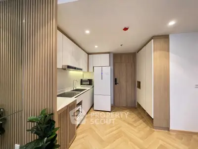 Modern kitchen with sleek cabinetry and herringbone flooring in a stylish apartment.