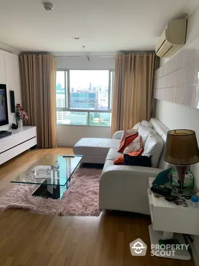 Spacious and well-lit living room with plush seating, modern amenities, and a captivating city view through large windows, perfect for urban living.