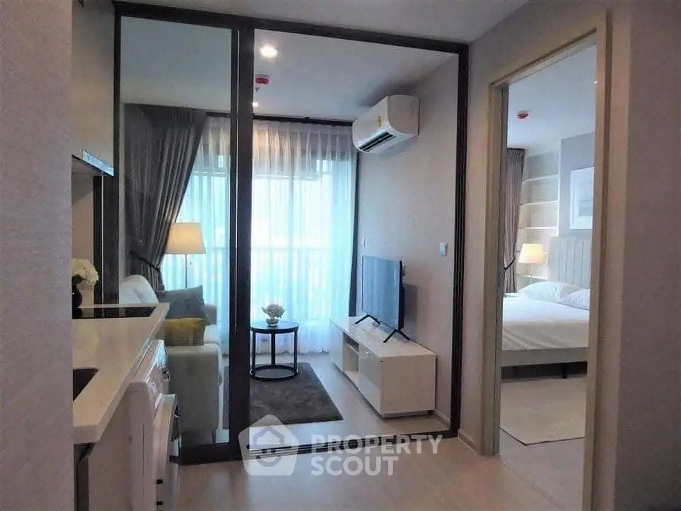 Modern apartment interior with cozy living room and bedroom, featuring sleek furniture and natural light.
