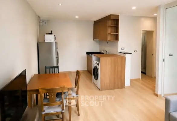 Modern apartment interior with open kitchen and dining area featuring wooden furniture and appliances.