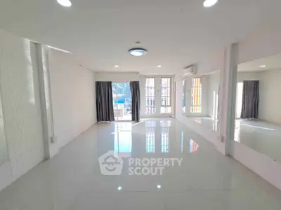 Spacious and bright living room with large windows and modern lighting.