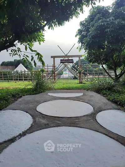 Charming garden pathway leading to a rustic wooden entrance, surrounded by lush greenery and serene outdoor ambiance.
