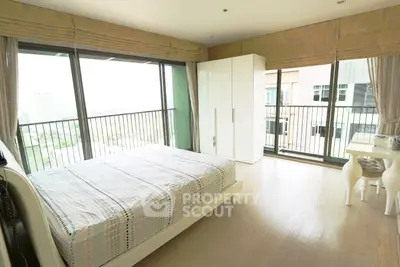 Spacious bedroom with large windows and balcony offering stunning city views.