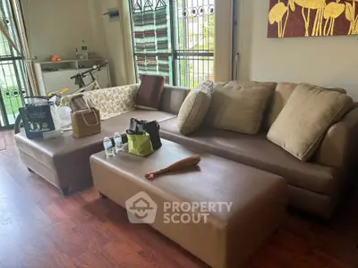 Cozy living room with modern brown leather sofa and wooden flooring, perfect for relaxation.