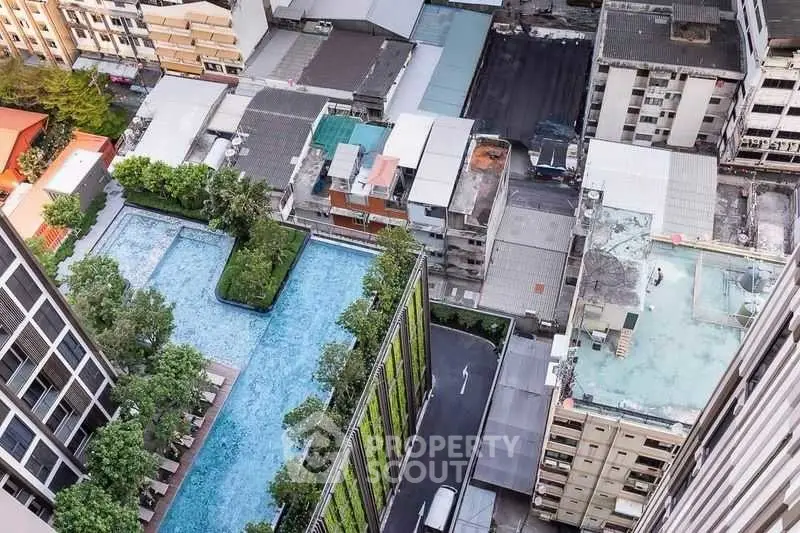 Stunning aerial view of urban residential complex with rooftop pool and lush greenery.