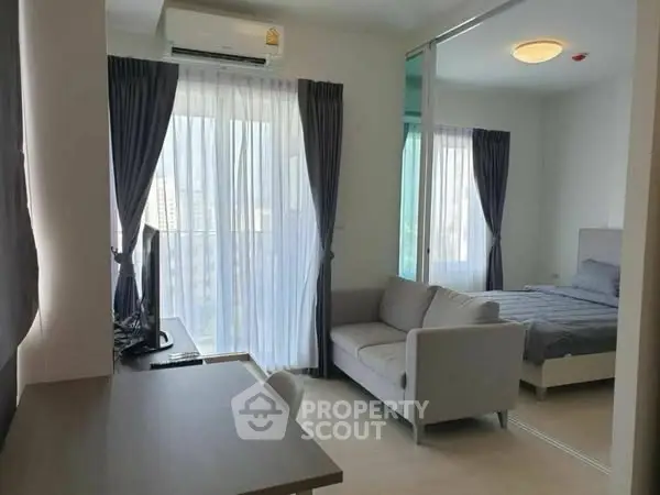 Modern apartment with cozy living area and bedroom, featuring large windows and stylish decor.
