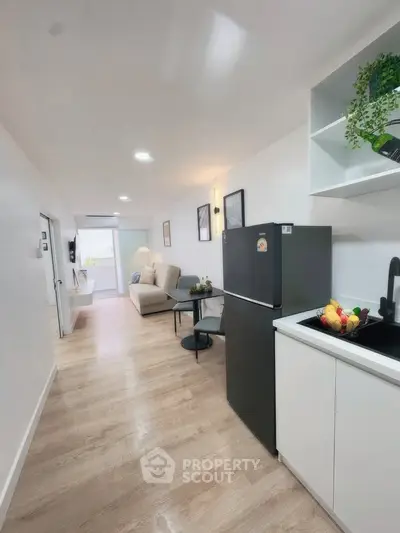 Modern open-layout kitchen and living room with sleek appliances and cozy seating area.