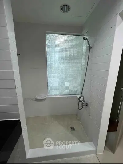 Modern bathroom with sleek shower design and frosted window for privacy.