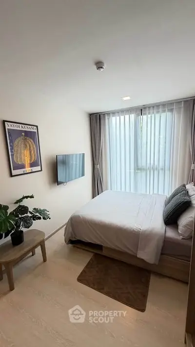 Modern bedroom with large window, wall-mounted TV, and stylish decor