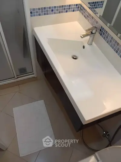 Modern bathroom with sleek sink and shower area, featuring elegant tile design.