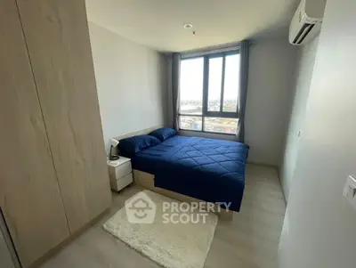 Modern bedroom with large window and blue bedding in high-rise apartment