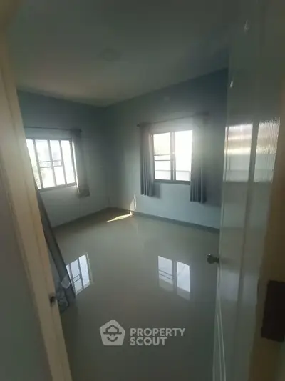 Spacious empty bedroom with large windows and glossy tiled floor