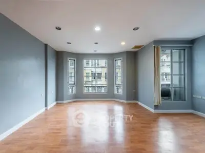 Spacious empty living room with large windows and wooden flooring in modern apartment.