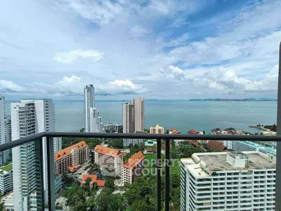 Stunning high-rise balcony view overlooking ocean and cityscape with lush greenery.
