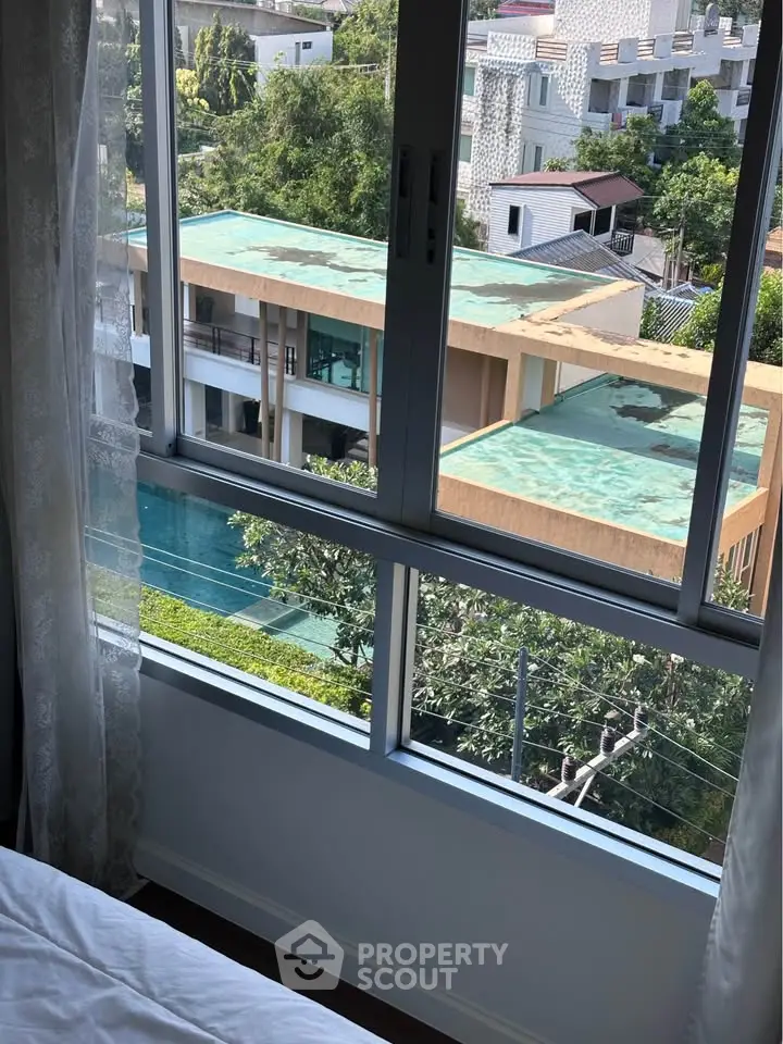 Stunning view from a bedroom window overlooking modern architecture and lush greenery.