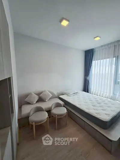 Modern bedroom with minimalist decor, featuring a cozy bed and stylish seating area, perfect for urban living.