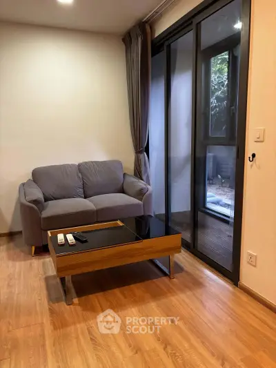 Cozy living room with modern sofa and glass sliding doors leading to a serene outdoor space.