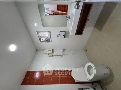 Modern bathroom with white tiles, shower, and toilet in a real estate property.