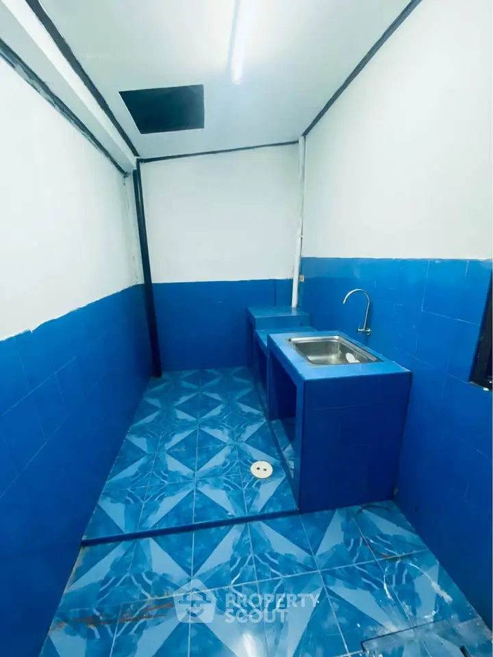Compact kitchen with vibrant blue tiles and a single sink, perfect for small spaces.