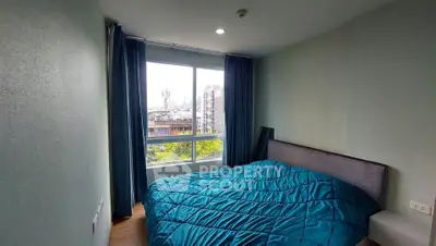 Cozy bedroom with large window offering city view and natural light