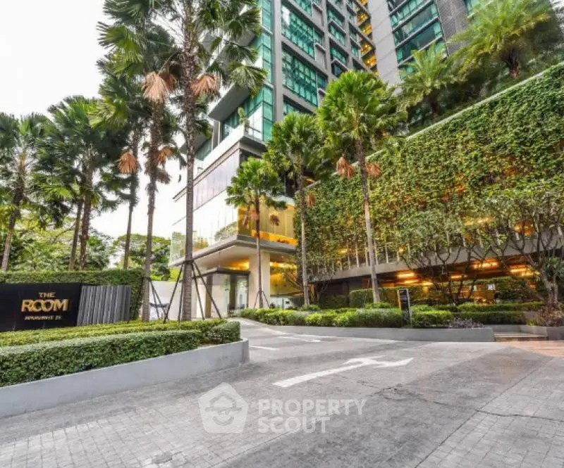 Luxurious modern condominium entrance with lush greenery and palm trees, offering an inviting and serene atmosphere.