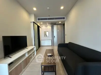 Modern living room with sleek black sofa and flat-screen TV, perfect for relaxation.