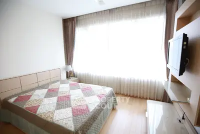 Bright and cozy bedroom with large window and modern TV setup