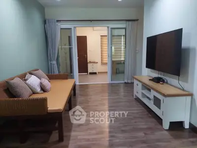 Spacious living room with modern decor and large TV, perfect for relaxation and entertainment.