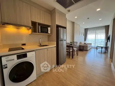 Modern open-layout kitchen and living room with wooden flooring and natural light.
