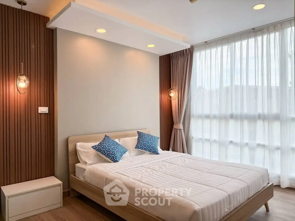 Modern bedroom with stylish lighting and large window for natural light.