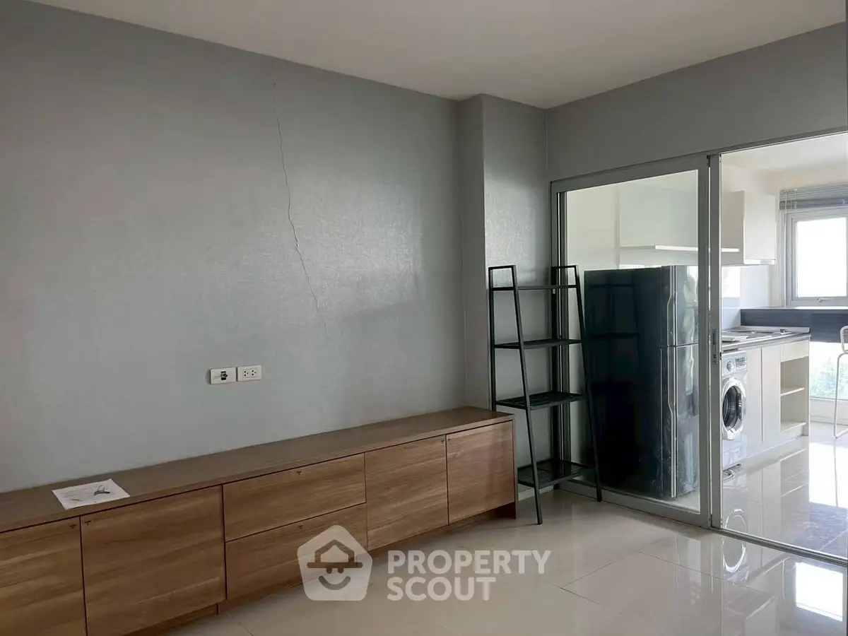 Modern apartment interior with sleek storage and glass partitioned kitchen area.