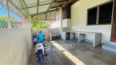Spacious outdoor area with tiled flooring and seating, perfect for relaxation or storage.