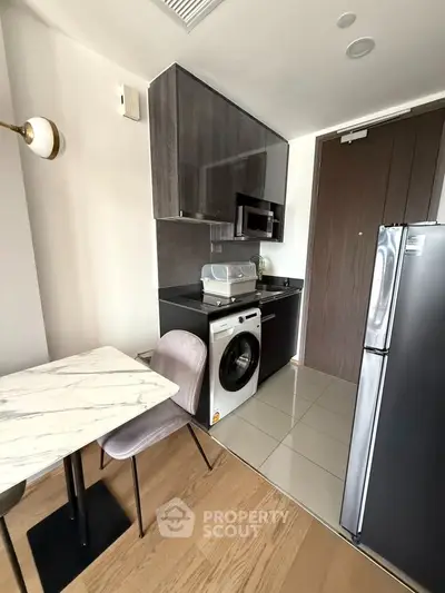 Modern compact kitchen with sleek appliances and stylish dining area in a contemporary apartment.