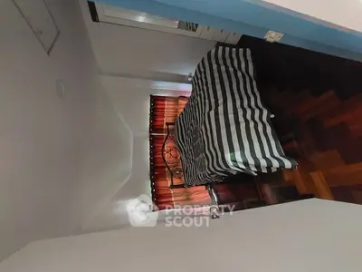 Cozy bedroom with striped bedding and wooden flooring