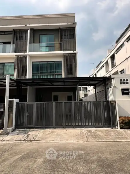 Modern multi-story townhouse with sleek facade and gated entrance in urban setting.