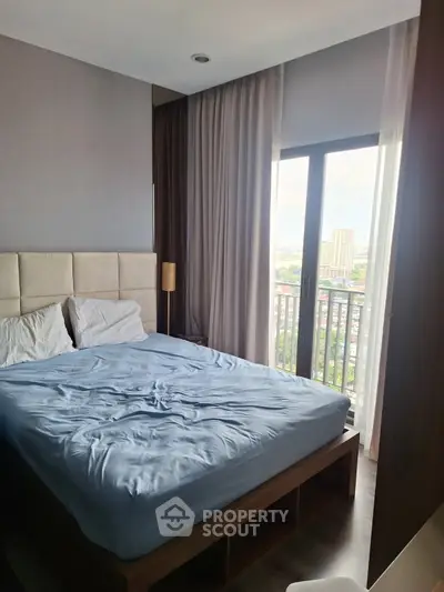 Modern bedroom with large window and city view, featuring a cozy bed and elegant decor.