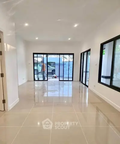 Spacious modern living room with large windows and glossy tiled floors