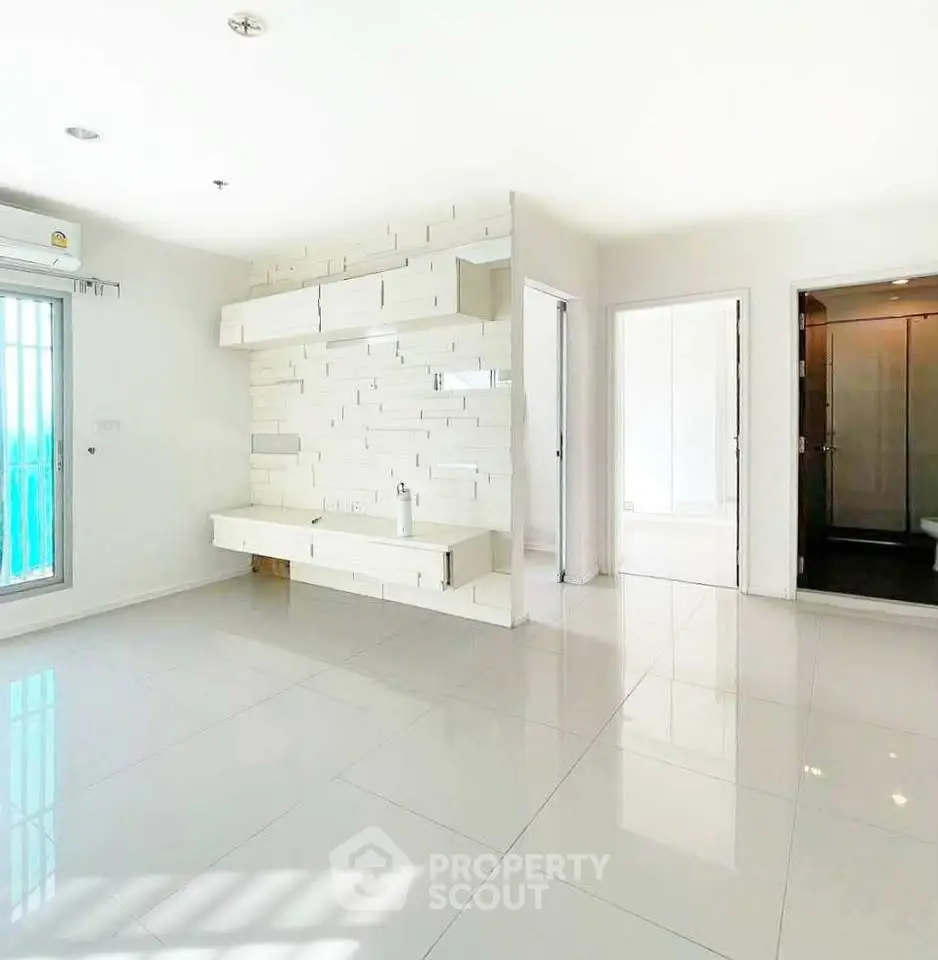 Spacious modern living room with sleek white tiles and built-in shelving, perfect for contemporary living.